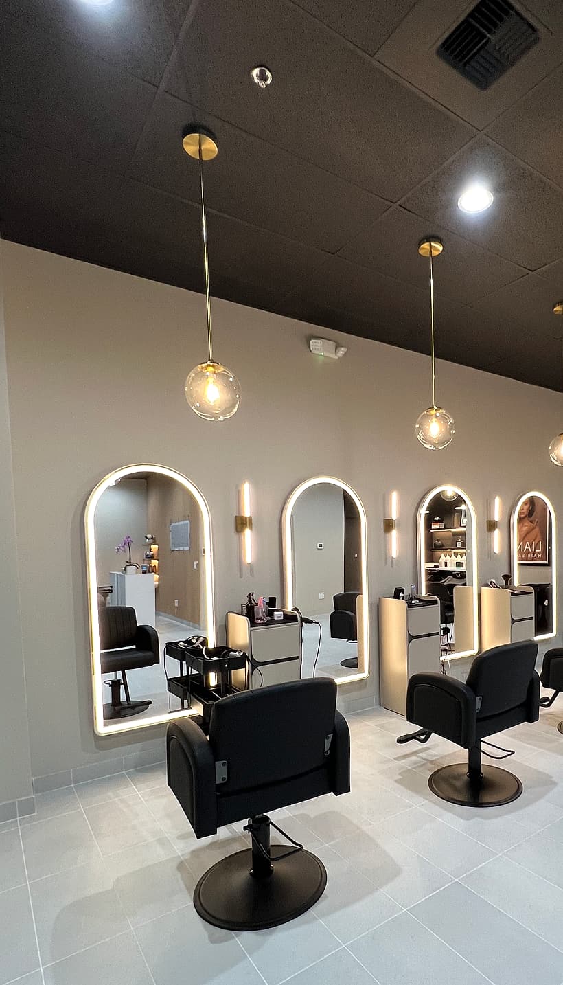 Arched illuminated mirrors and black styling chairs inside Liana Hair Salon on Denny Way, Seattle