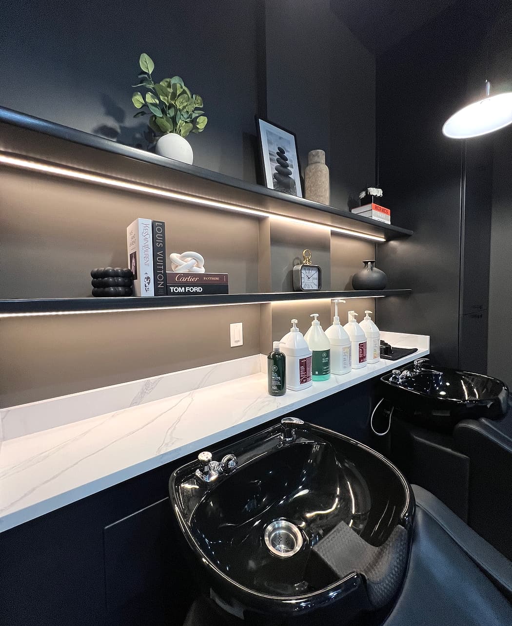 Black shampoo basin and backlit shelf in the wash room at Liana Hair Salon, Seattle